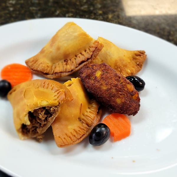 Fords BBQ empanadas and a fried croquette, garnished with carrots and olives on a white plate.