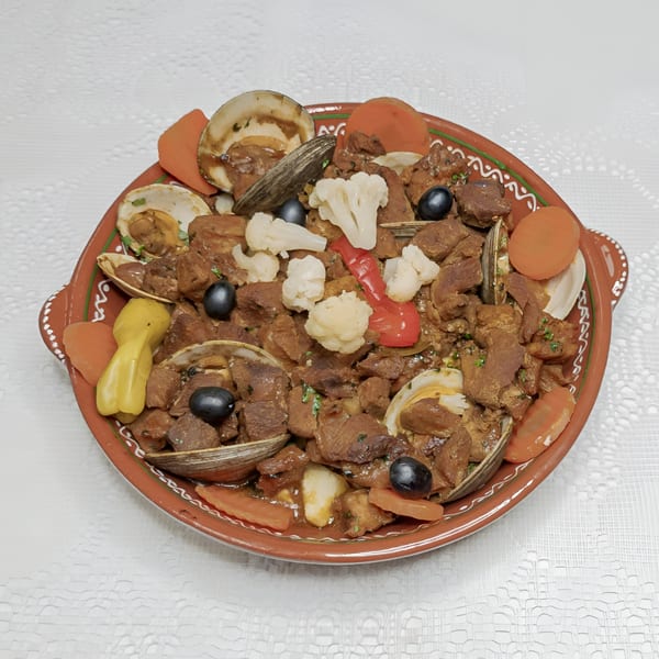 Fords BBQ's hearty stew with meat, clams, olives, cauliflower, and peppers in a rustic bowl.