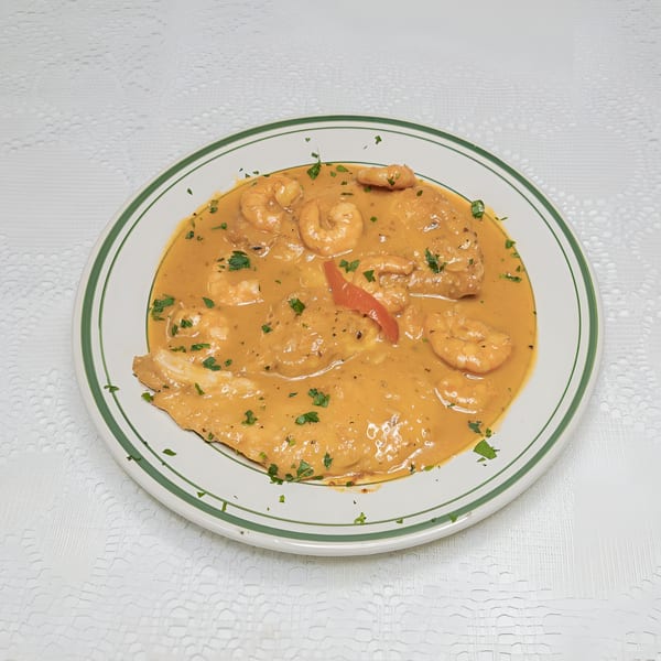 A plate of shrimp and fish in a creamy orange sauce, garnished with parsley.